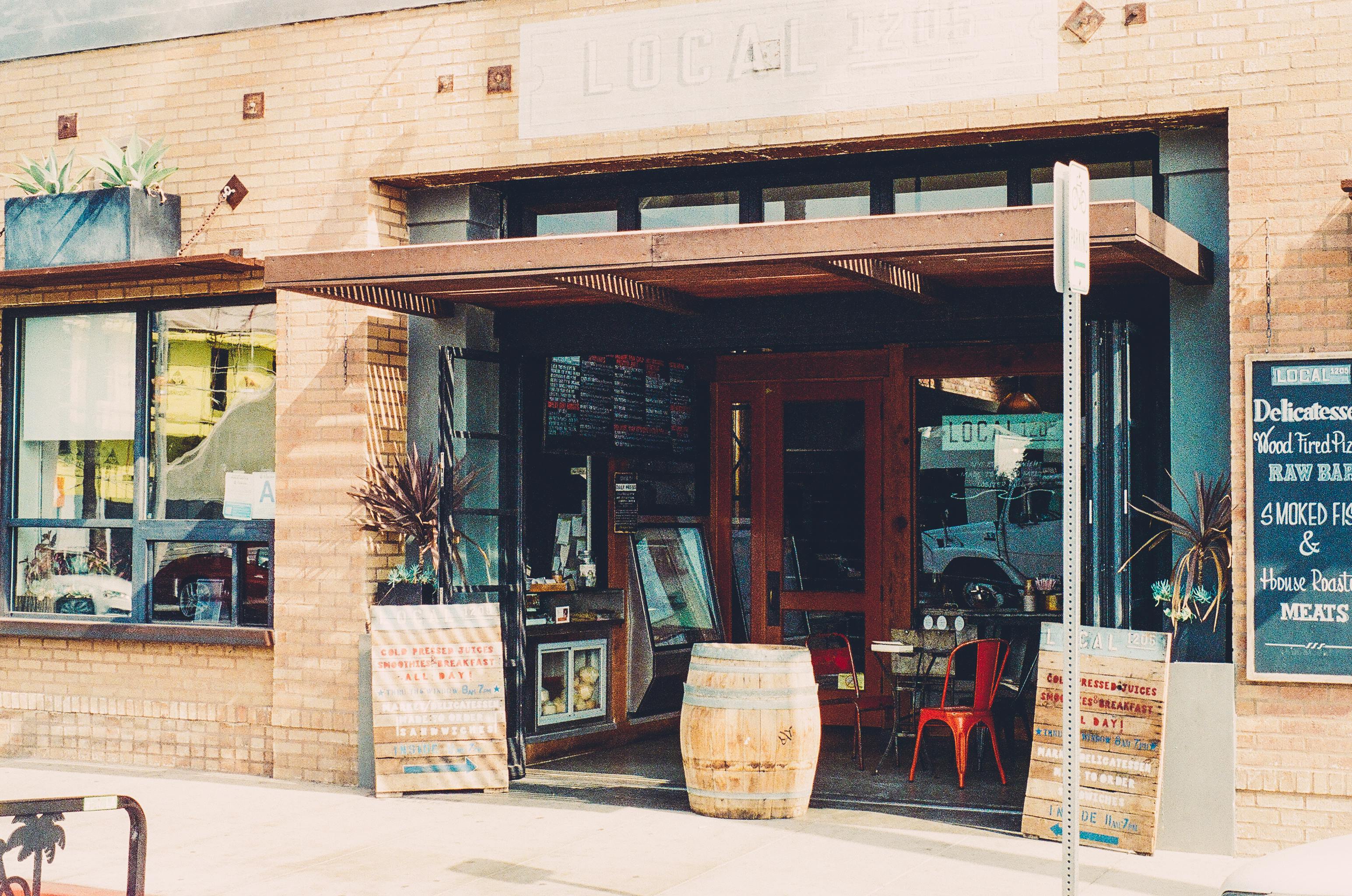 Local delicatessen storefront open for business with chalkboard menus outside